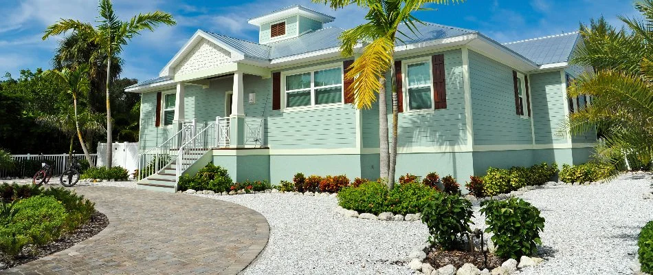 Blue beach house in Deerfield Beach, FL, with a rock landscape and plants.