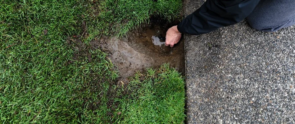 Worker repairing a sprinkler head near concrete in West Palm Beach, FL.