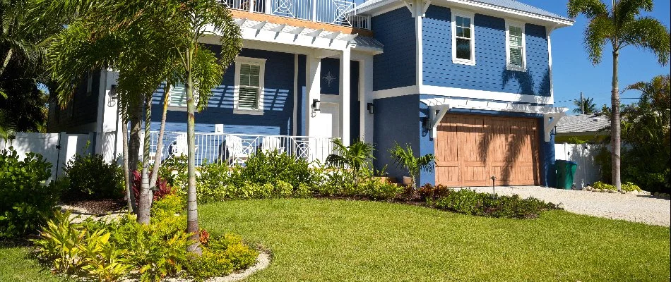 A blue house in Boynton Beach, FL, with grass and tropical plants.