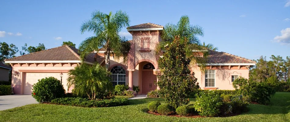 Pink house in Royal Palm Beach, FL, with a lawn and tropical landscaping